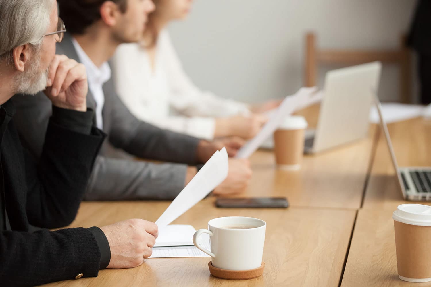 businessman holding documents focused on listening at group meeting
